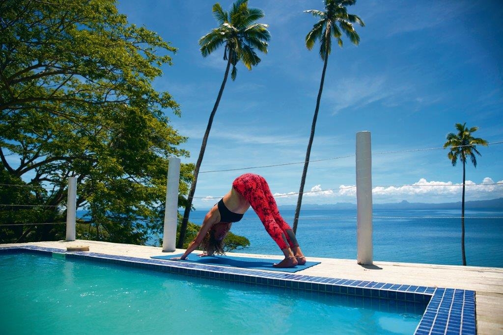 A woman does yoga next to the pool at a Bayview Heights Villa at Daku Resort, Savusavu.